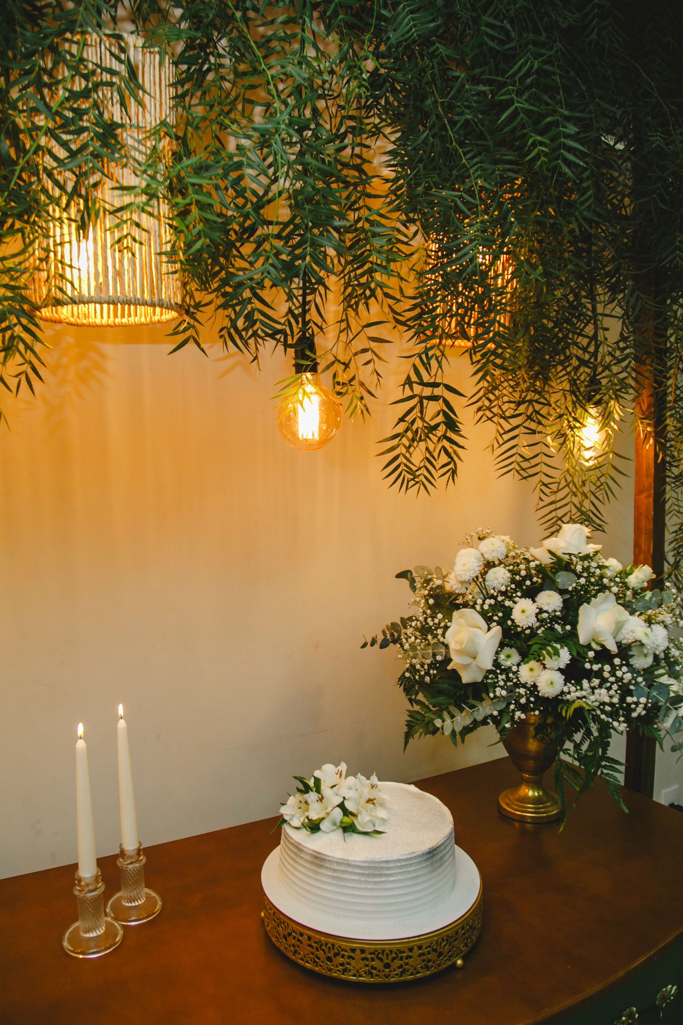 Minimal wedding cake styled with white florals and hanging greenery